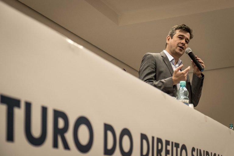 Imagem de palestrando advogado do escritório do Paraná, Nasser Allan com microfone falando 
